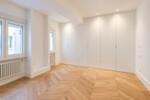 Dormitorio minimalista con armarios blancos y suelo de roble