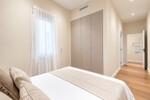 Dormitorio minimalista con armario empotrado y pasillo luminoso