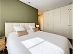 Dormitorio minimalista con pared oliva