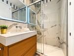 Ba&ntilde;o moderno con ducha de m&aacute;rmol y espejo iluminado