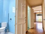 Pasillo luminoso con ba&ntilde;o azul y balc&oacute;n
